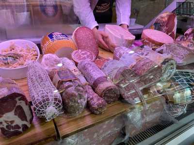 Davanti a noi il bancone espone in bella vista mortadella, fesa di tacchino, speck, bresaola e salame